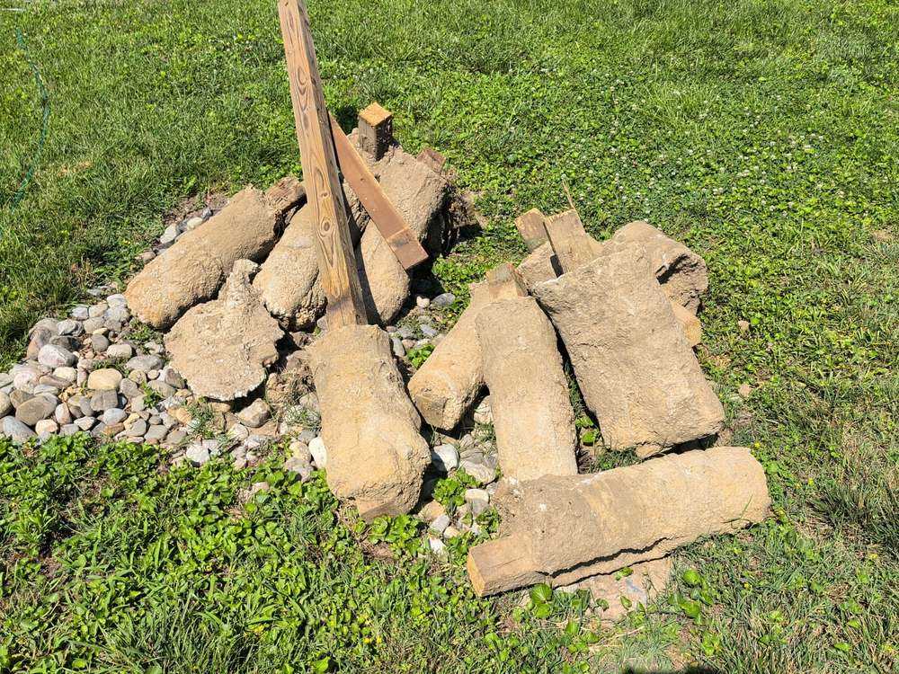 Pile of broken concrete fence footings and a pressure-treated post before removal in Annapolis, MD