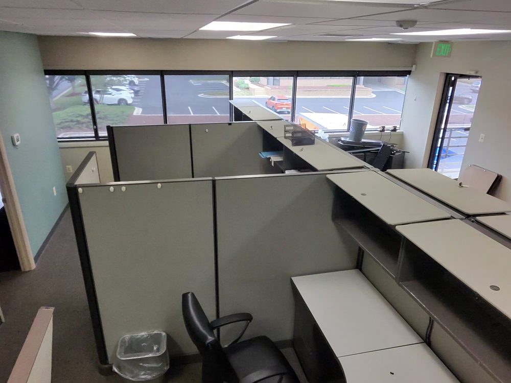 Rows of cubicle workstations and office chairs staged for removal in Annapolis, MD