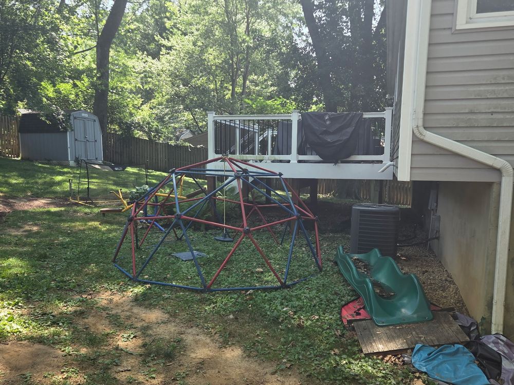 Metal dome jungle gym and slide beside a deck before backyard cleanout in Arnold, MD