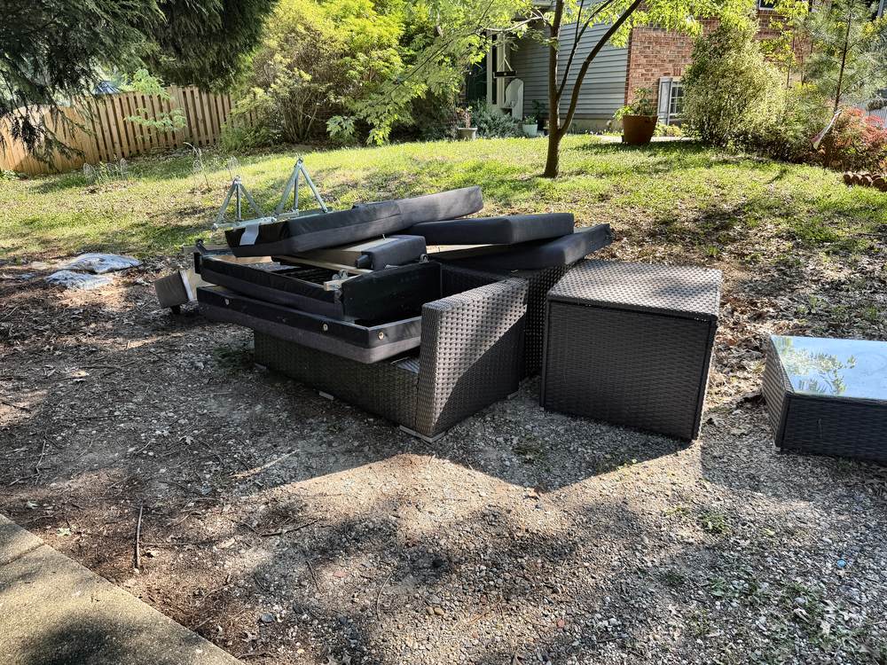 Wicker patio sectional, cushions and storage boxes stacked for removal in Arnold, MD