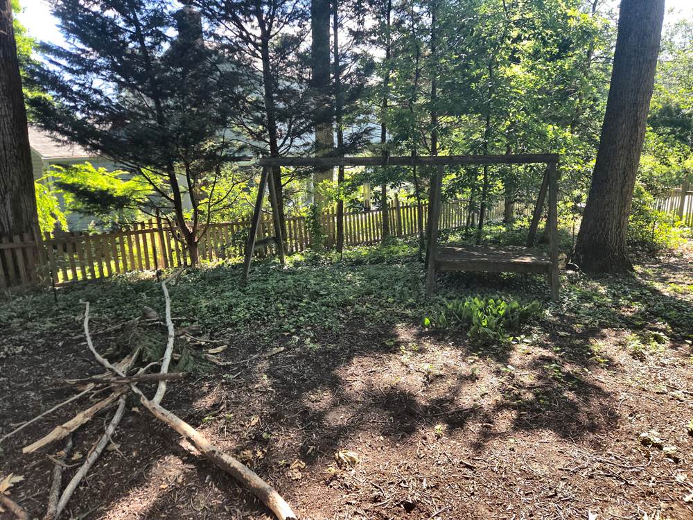 Weathered wooden swing set frame and brush pile before removal in Arnold, MD