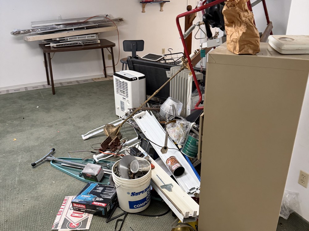Packed basement rec room full of tools, exercise gear and clutter before a prelisting cleanout in Catonsville, MD