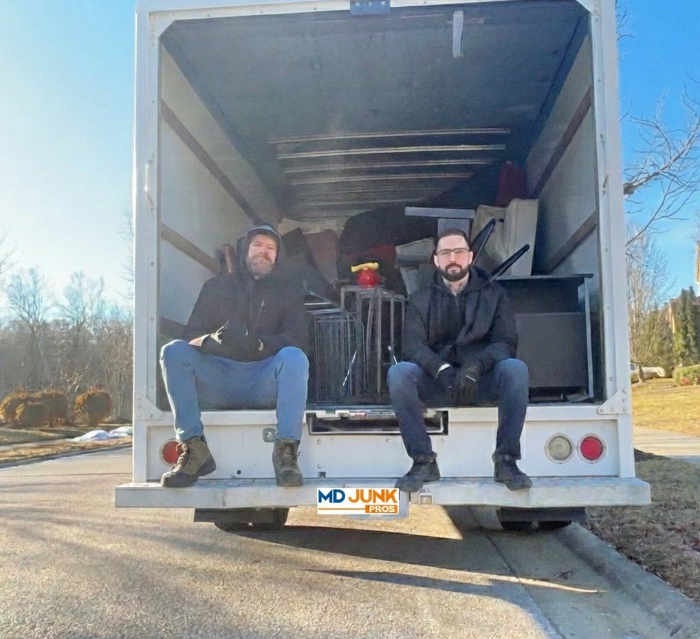 Chris and Max, founders of MD Junk Pros, sitting on the back of their junk removal truck in Hanover, Maryland