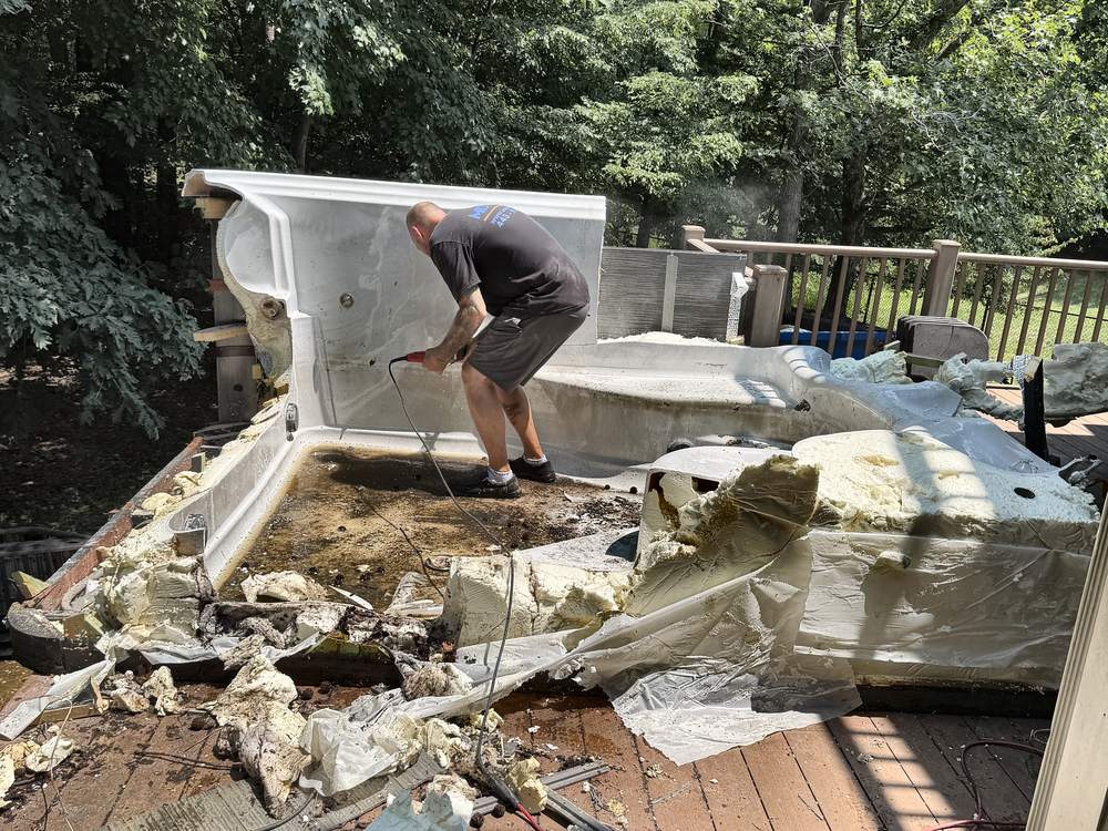Crew cutting a swim spa shell apart with foam and framing exposed during demolition in Clarksville, MD