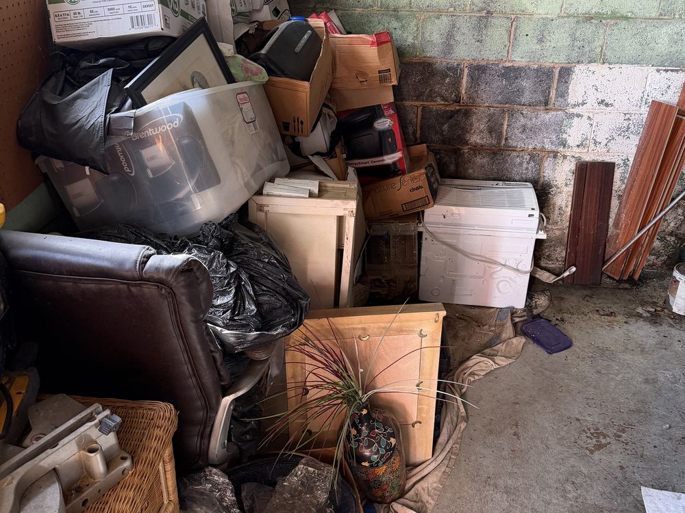 Basement corner piled with boxes, a window AC unit and a recliner before a cleanout in Allview Estates, Columbia, MD