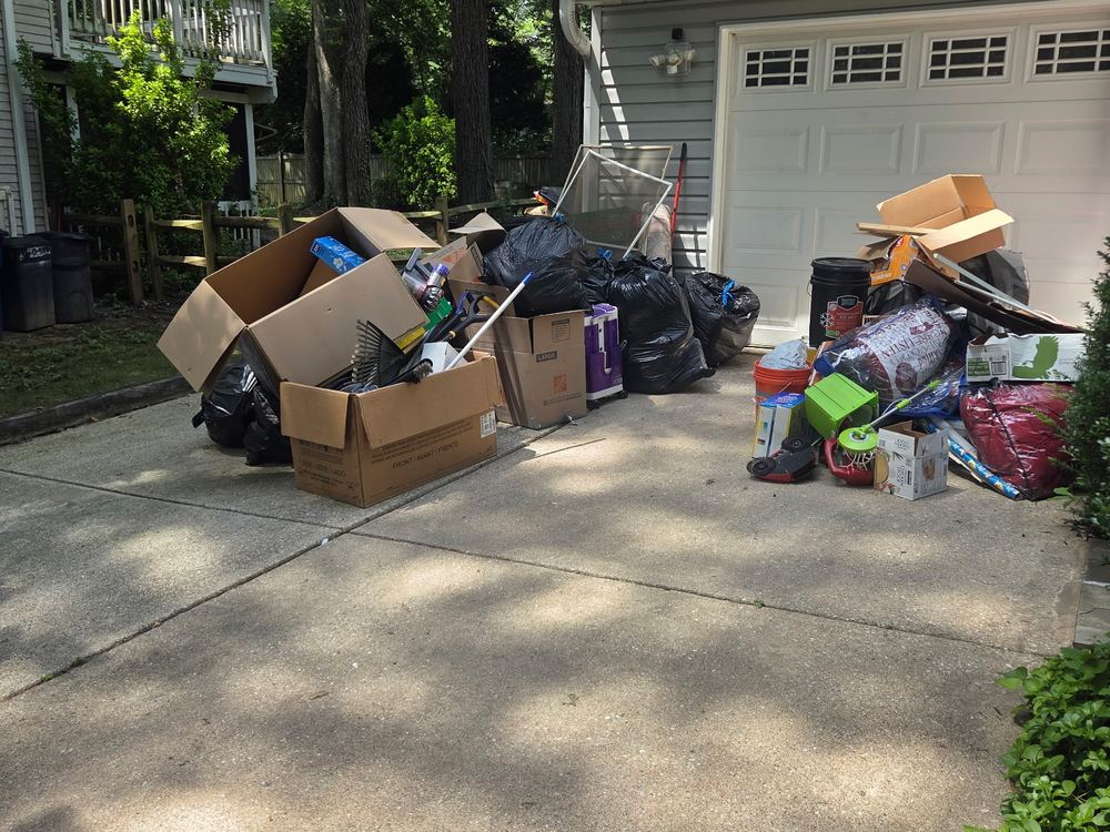 Driveway staged with boxes, bags and yard tools before a garage cleanout in Hickory Ridge, Columbia, MD