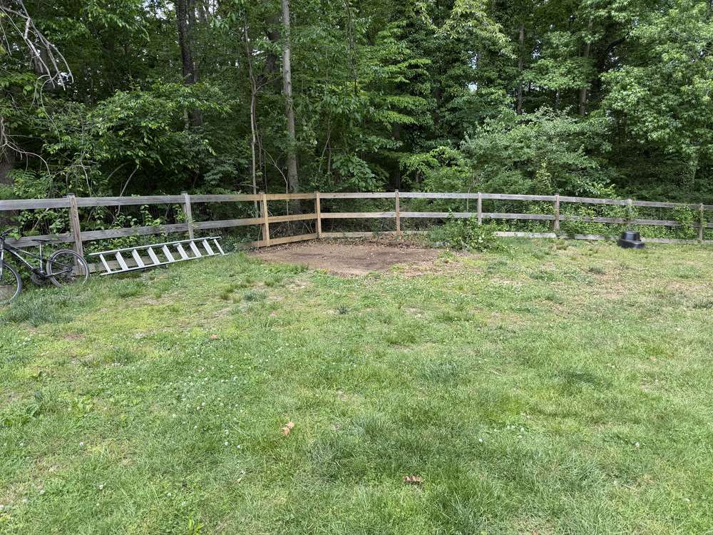 Cleared grass pad along the fence line after full shed demolition in Davidsonville, MD