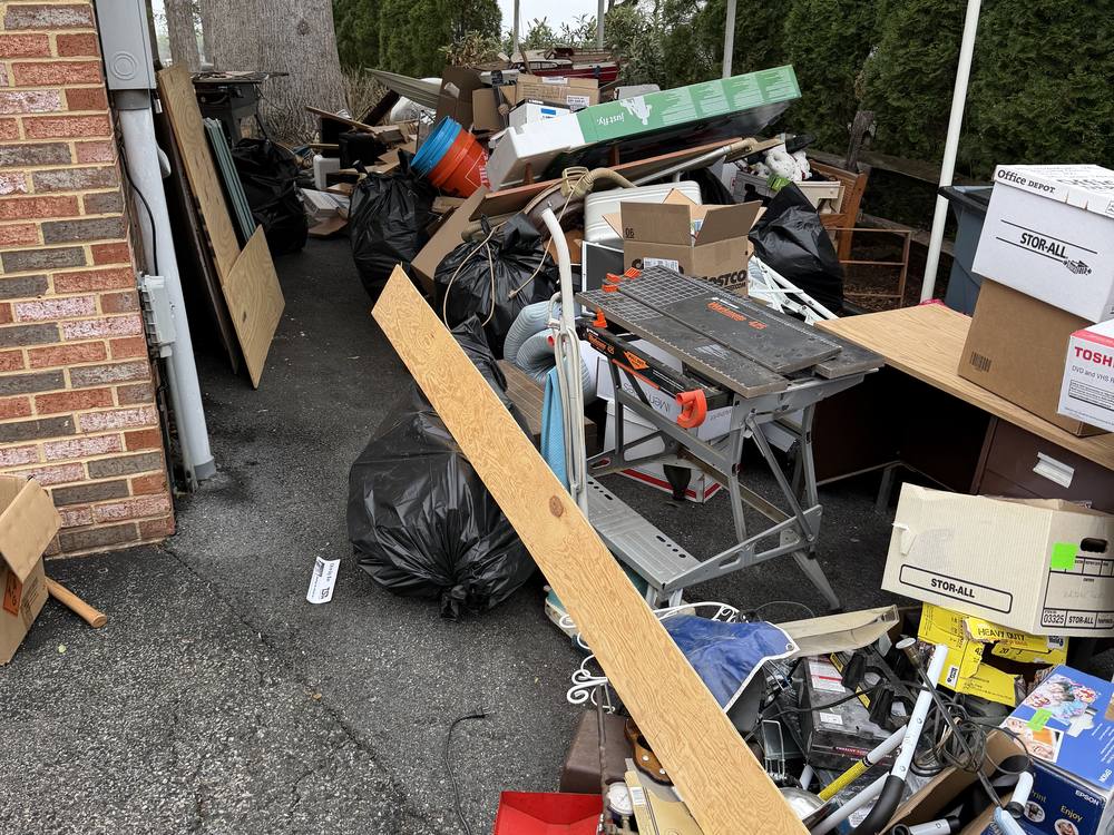 Driveway staged with bagged trash, boxes, tools and household goods before an estate cleanout in Edgewater, MD