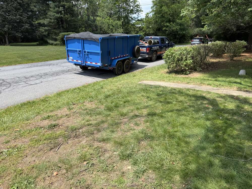 Loaded and tarped dump trailer with the lawn cleared after an estate cleanout in Ellicott City, MD