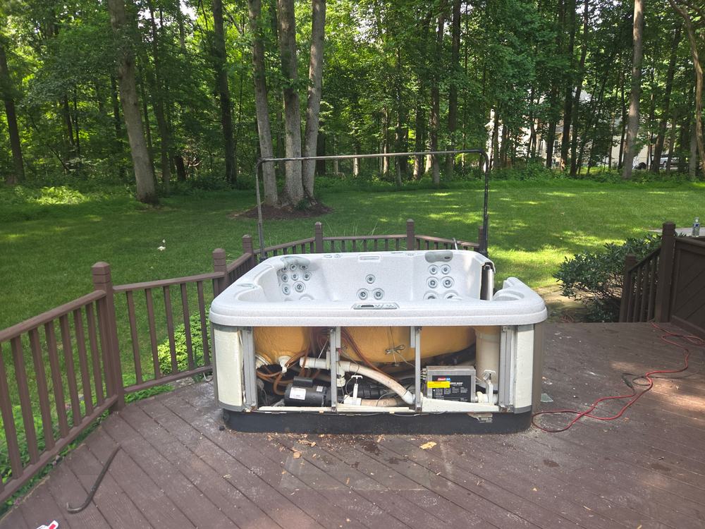 Hot tub on a backyard deck with side panels off and plumbing exposed before removal in Ellicott City, MD