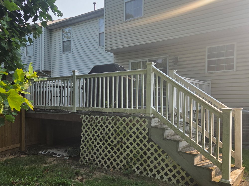 Old raised wood deck with railings, lattice skirting, and stairs off the back of a home before demolition in Ferndale, MD