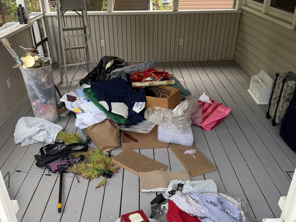 Screened porch packed with bags, boxes, and household clutter before a pre-listing cleanout in Ferndale, MD