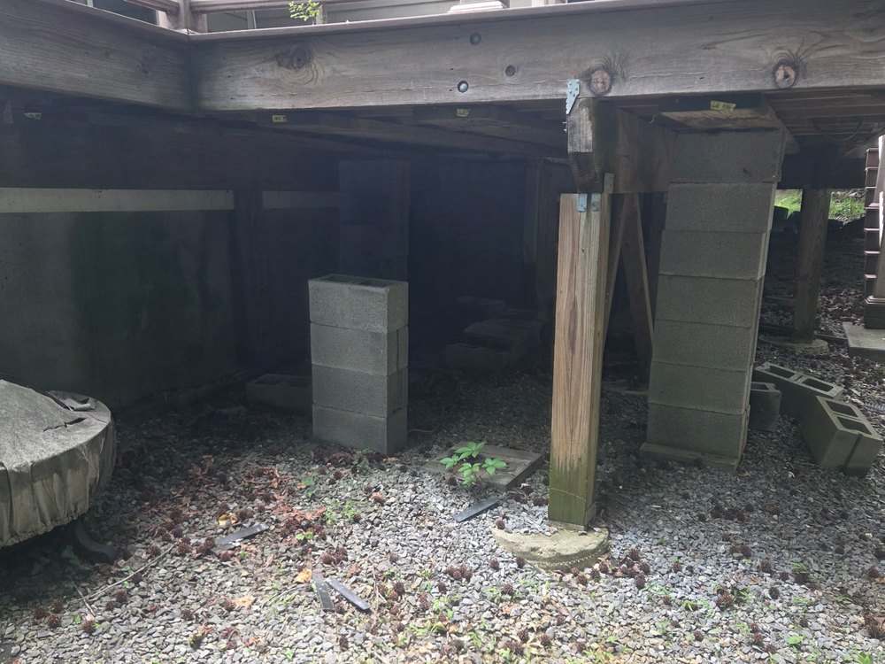 Stack of loose cinder blocks and debris under a raised backyard deck before removal in Fulton, MD