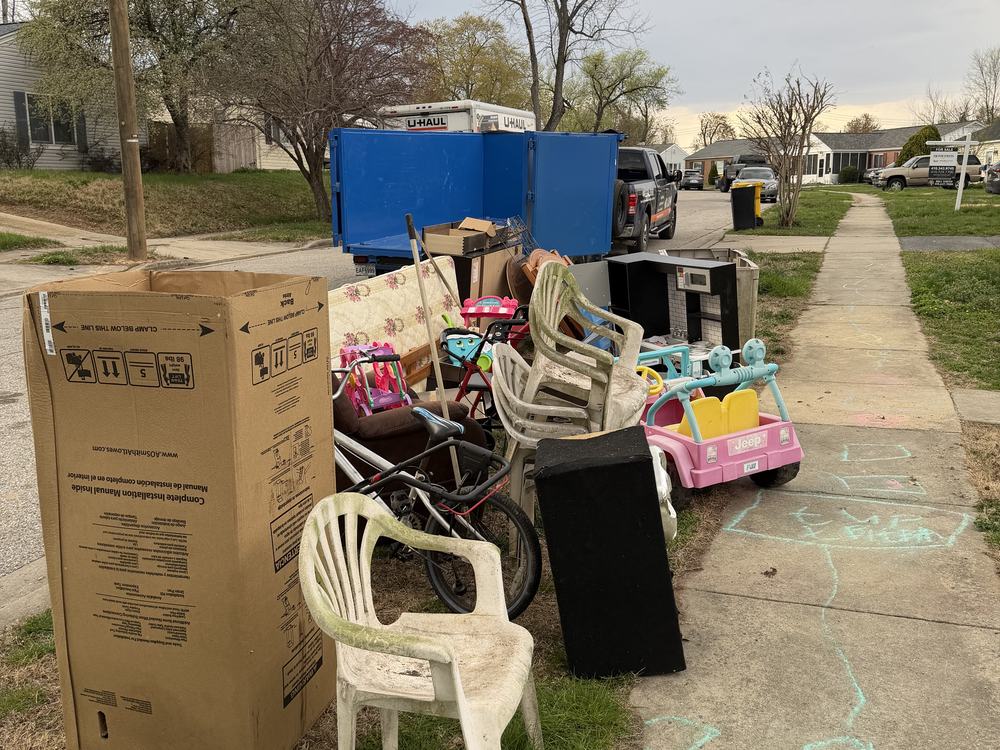 Curbside pile of furniture, toys, a Power Wheels Jeep and mattresses staged for a house cleanout on Jupp Road in Glen Burnie, MD