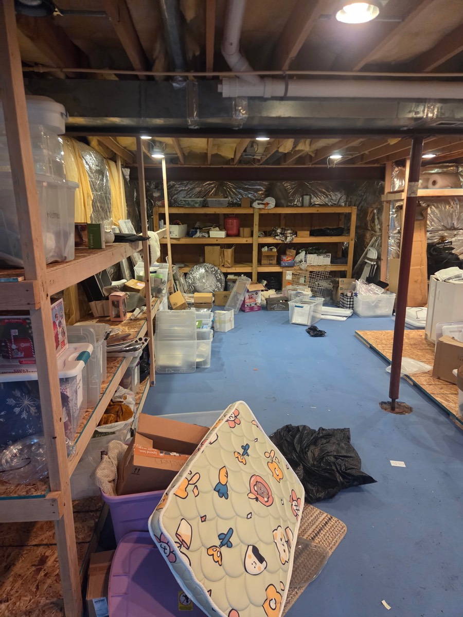 Basement storage area filled with boxes, bins, household items, and loose belongings before an estate cleanout on Kennard Drive in Glenelg, MD