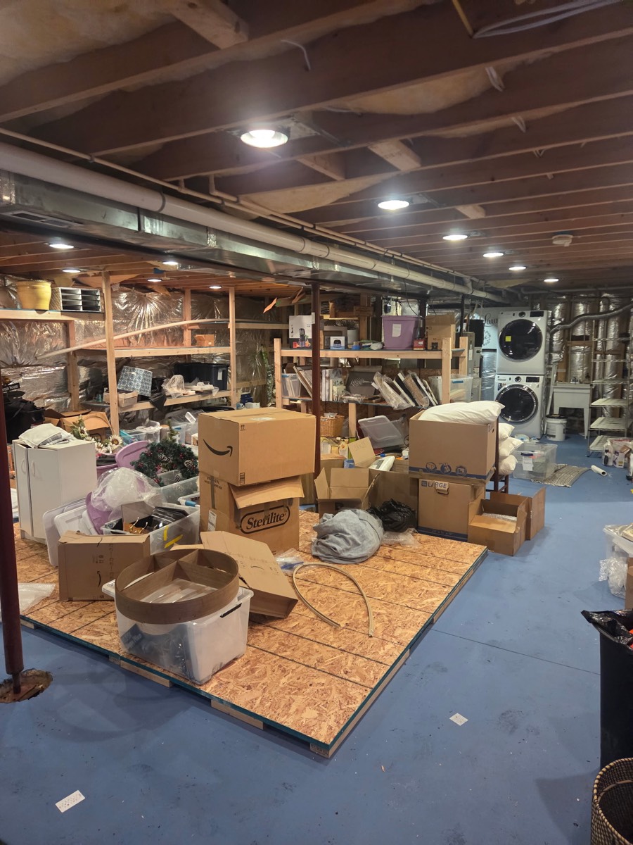 Large basement storage area with boxes, seasonal items, and household belongings before an estate cleanout on Kennard Drive in Glenelg, MD
