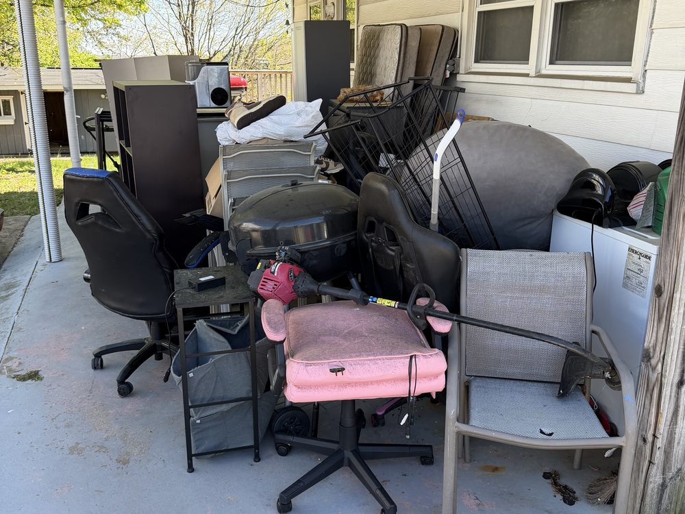 Carport packed with office chairs, a grill, dresser, washer and mattress before a cleanout on 11th Street in Old Town Laurel, MD