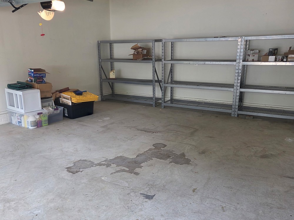 Swept-out two-car garage with an empty floor and clear shelving after a garage cleanout in Millersville, MD