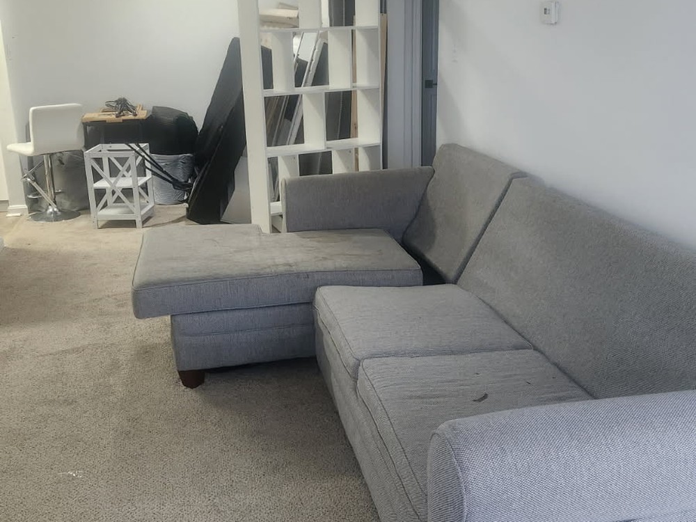 Furnished apartment living room with a gray sectional and cube shelving before a move-out cleanout in Seven Oaks, Odenton, MD