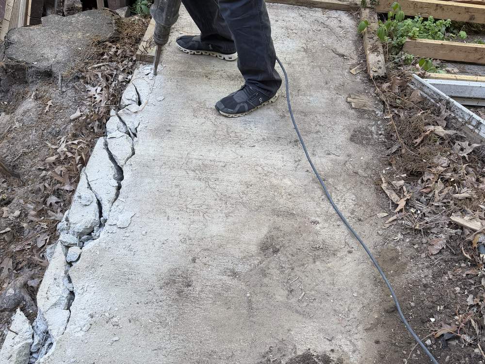 Concrete pad being broken apart with a jackhammer before removal in Pasadena, MD