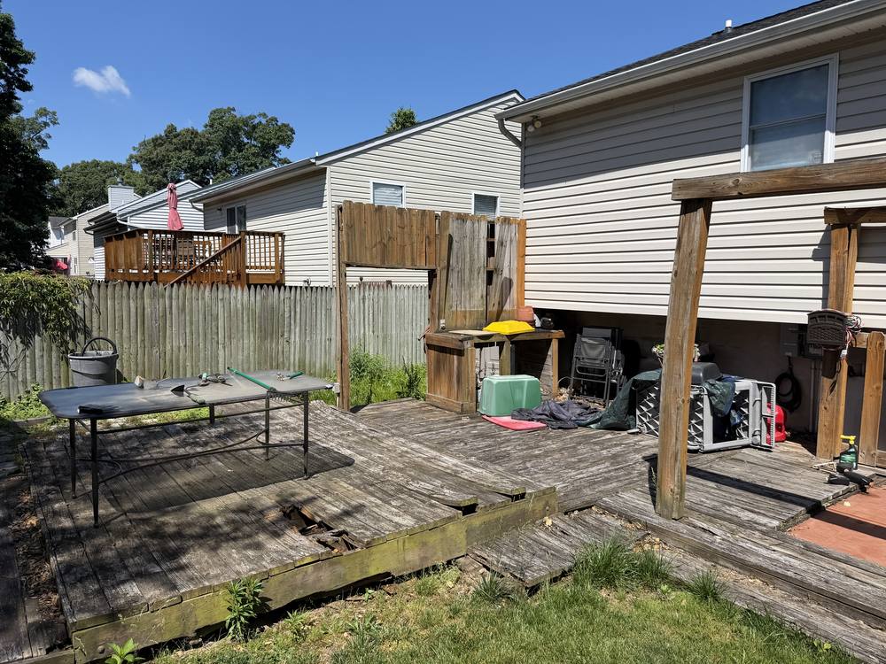 Rotted backyard deck with holes in the boards before demolition in Pasadena, MD