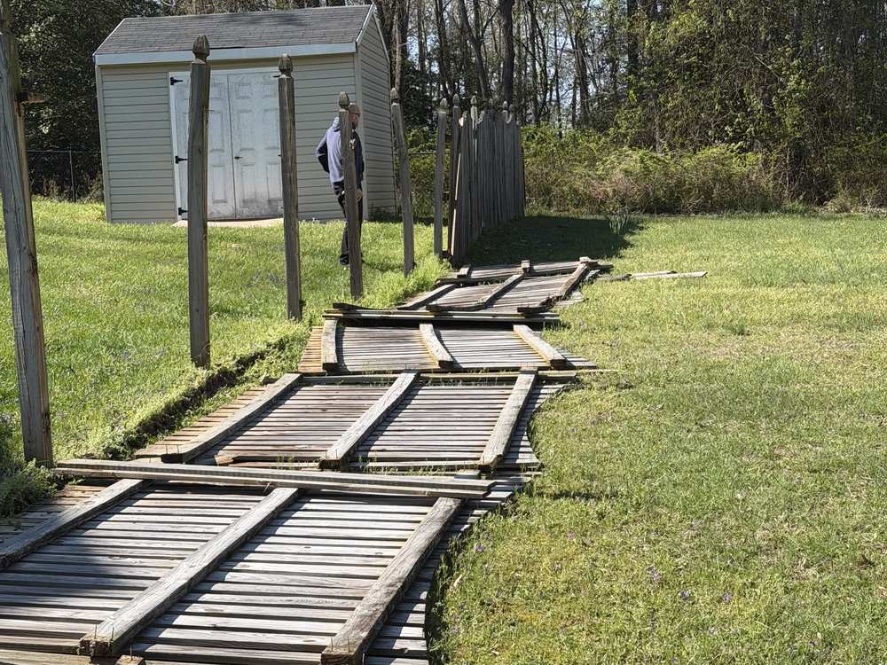 Dismantled wooden fence sections laid across the lawn before haul away in Pasadena, MD