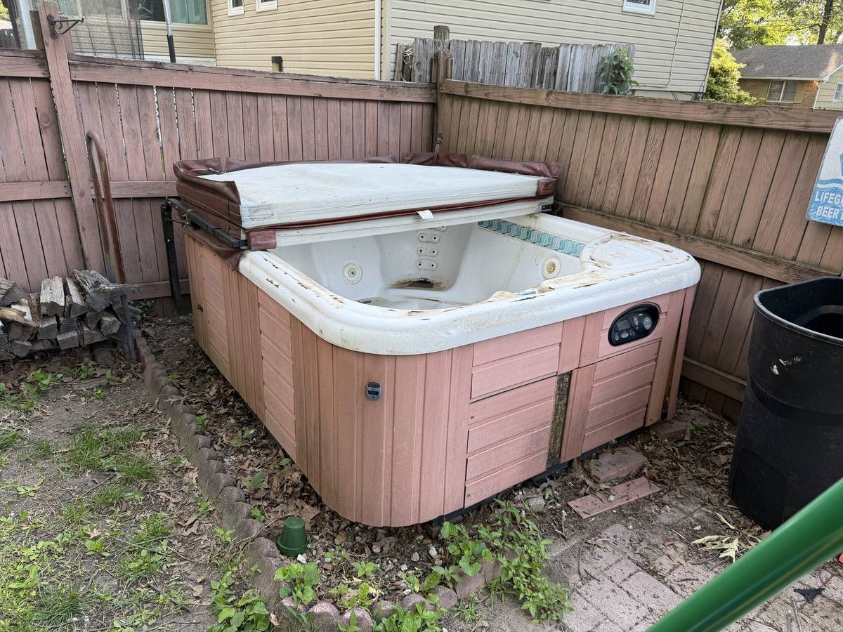 Old hot tub in the corner of a fenced backyard before hot tub removal in Severna Park, MD